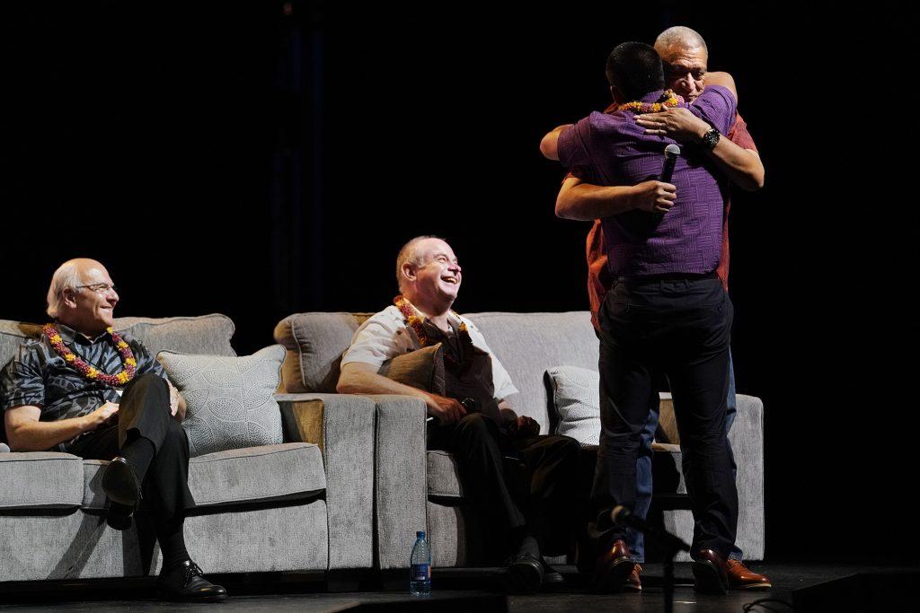 Kauai Mayor Derek Kawakami hugs Maui Mayor Richard Bissen after opening with a sentimental appreciation for the neighbor island leaders after the Aug. 8 fires Wednesday, Nov. 16, 2023, at the 22nd Native Hawaiian Convention at Maui Arts & Culture Center in Kahului. The mayors including Honolulu Mayor Richard Blangiardi, seated left, and Hawaii County Mayor Mitch Roth were part of a panel discussion Hawaii’s Mayors: A Collective Commitment to Housing.(Kevin Fujii/Civil Beat/2023)